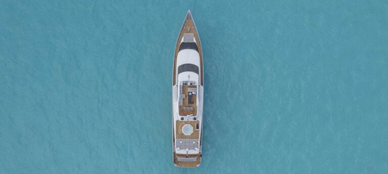 Wide aerial view of 110 ft Avalon luxury charter yacht anchored alone on translucent turquoise Caribbean sea near Cancun Riviera Maya