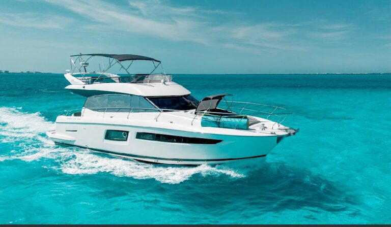 Side view of 55 ft Prestige 500 luxury flybridge yacht charter underway in vivid turquoise Caribbean waters near Cancun, sleek white hull with bimini top and wake trailing