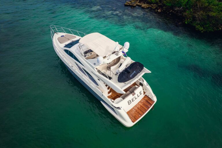 Starboard side view of the 58 ft Azimut luxury yacht rental moored in calm turquoise water with lush tropical forest backdrop at Puerto Aventuras marina, Riviera Maya yacht charter