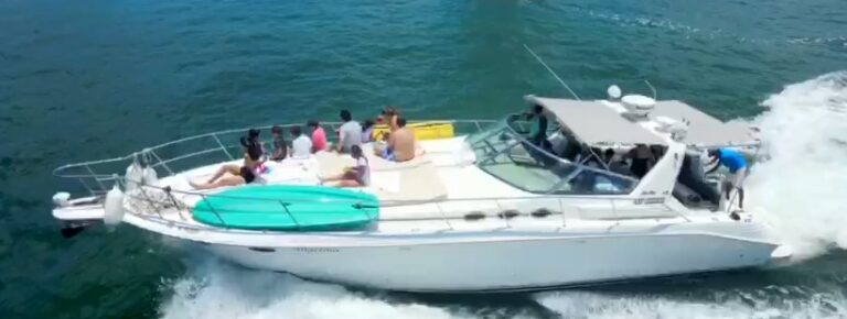 Aerial view of 43 ft Sea Ray Angelina luxury yacht charter underway with large group of guests on deck, surfboard and floats aboard, Caribbean sea, Cancun rental