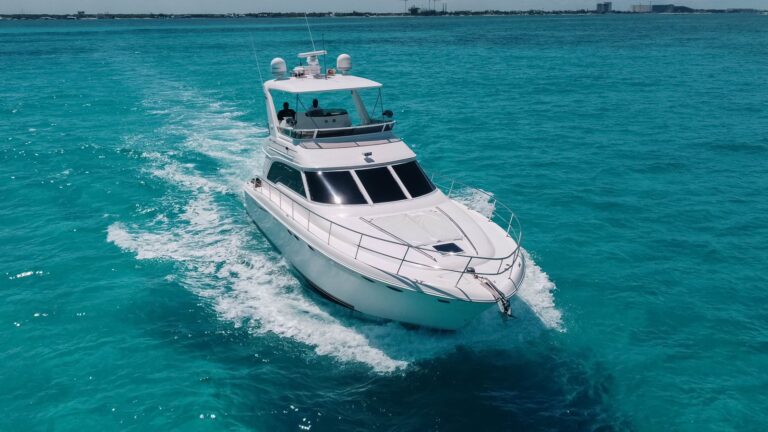 Front aerial view of 53 ft Sea Ray flybridge yacht SeaCastle luxury charter speeding across turquoise Caribbean water near Cancun, crew visible on flybridge