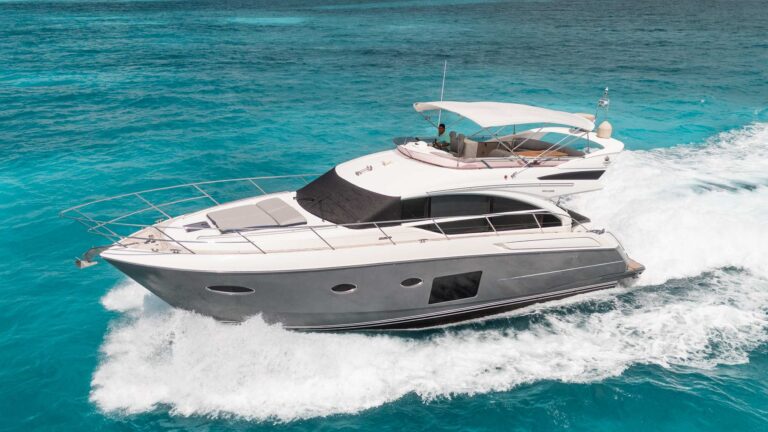 56 ft Princess flybridge luxury yacht cruising through turquoise Caribbean waters near Cancun, aerial port side view, yacht charter rental for 12 people